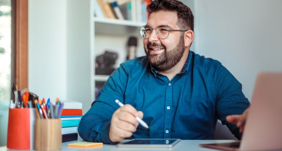 Smiling adult man at desk iStock 1270233943 min